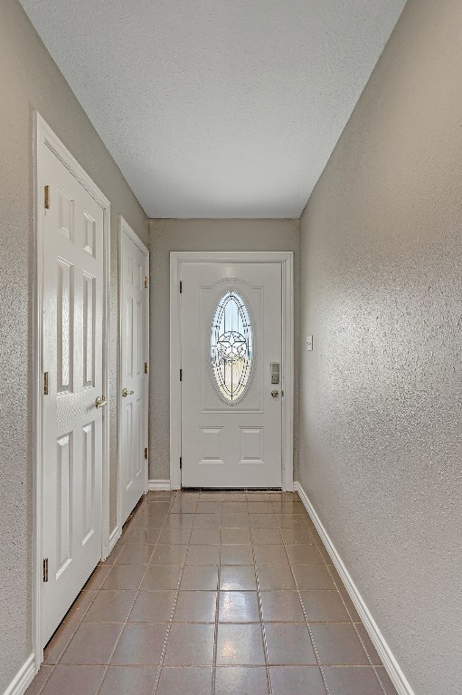 doorway to outside featuring light tile floors and a textured ceiling