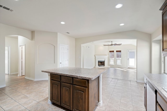 kitchen featuring light tile patterned flooring, dark brown cabinets, stainless steel dishwasher, and vaulted ceiling