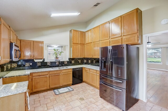 kitchen with decorative backsplash, sink, appliances with stainless steel finishes, and vaulted ceiling