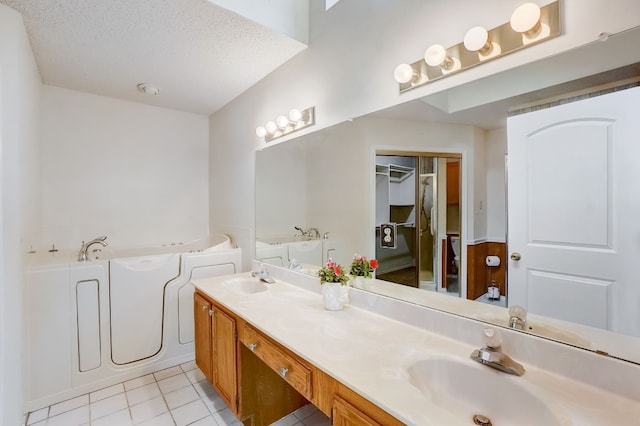 bathroom featuring vanity, a textured ceiling, tile patterned floors, and a bathing tub