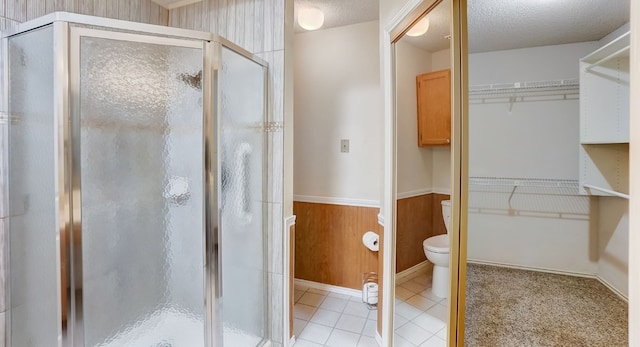 bathroom featuring a textured ceiling, wooden walls, and walk in shower