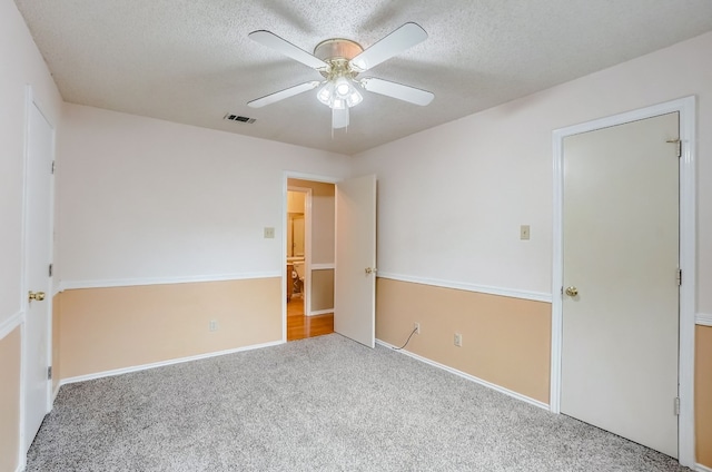 carpeted spare room featuring ceiling fan and a textured ceiling