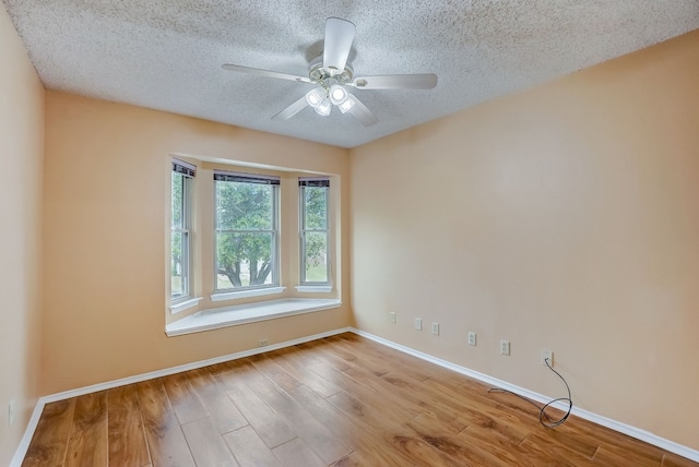 empty room featuring ceiling fan, light hardwood / wood-style floors, and a textured ceiling