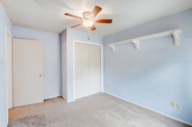 unfurnished bedroom featuring ceiling fan, light colored carpet, a textured ceiling, and a closet