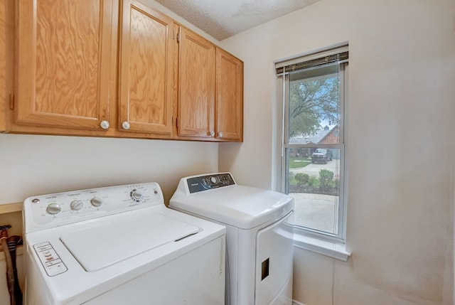 laundry area featuring cabinets, a textured ceiling, and washer and clothes dryer