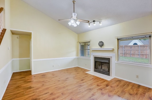 unfurnished living room featuring a textured ceiling, ceiling fan, high vaulted ceiling, a fireplace, and light hardwood / wood-style floors