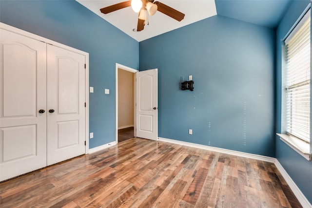 unfurnished bedroom with lofted ceiling, hardwood / wood-style floors, ceiling fan, and a closet