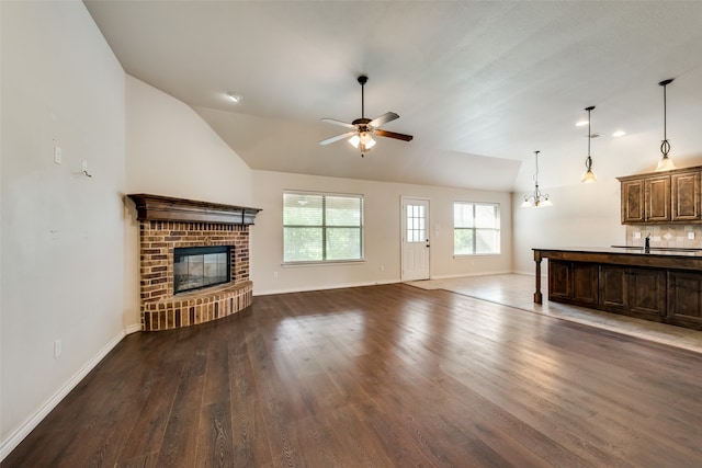 unfurnished living room featuring a brick fireplace, vaulted ceiling, ceiling fan, and dark hardwood / wood-style floors