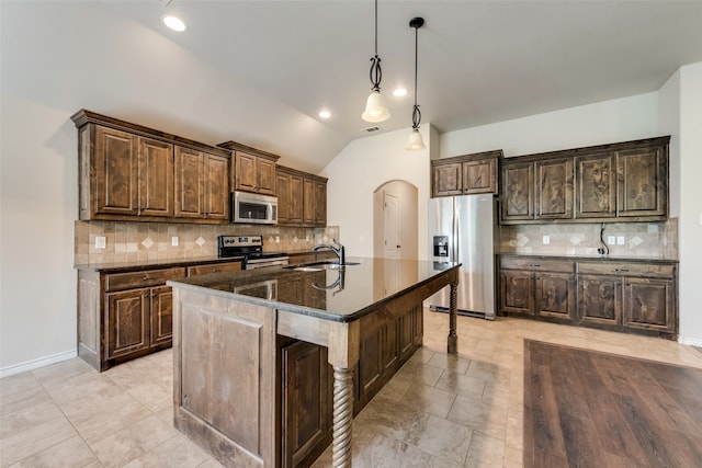 kitchen featuring appliances with stainless steel finishes, pendant lighting, lofted ceiling, a kitchen island with sink, and sink