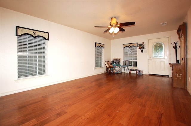 sitting room with ceiling fan and dark wood-type flooring