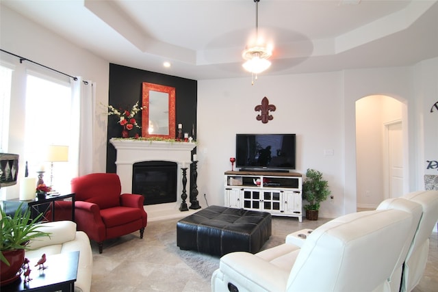 tiled living room featuring ceiling fan and a tray ceiling