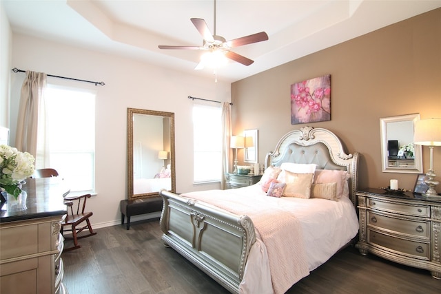 bedroom featuring dark hardwood / wood-style flooring, ceiling fan, and a raised ceiling