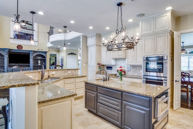 kitchen with hanging light fixtures, a center island with sink, and stainless steel double oven