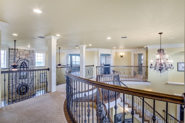 hallway with ornate columns, a notable chandelier, carpet, and crown molding