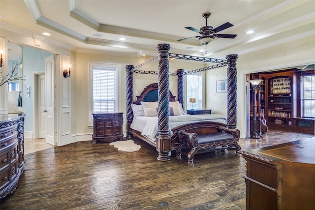 bedroom featuring dark hardwood / wood-style flooring, ceiling fan, crown molding, and a raised ceiling