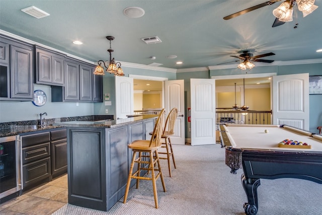 kitchen featuring ceiling fan, a kitchen island, light carpet, pool table, and decorative light fixtures