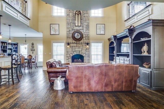 living room featuring plenty of natural light, a towering ceiling, and dark hardwood / wood-style floors