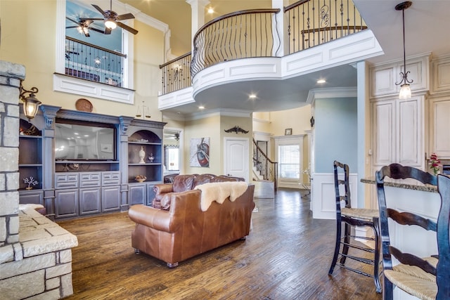 living room with ornamental molding, dark hardwood / wood-style flooring, ceiling fan, and a towering ceiling