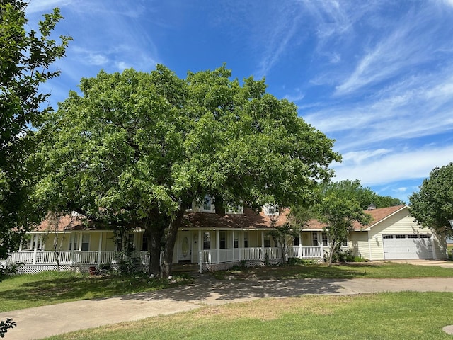 view of front of home with a garage, a front yard, and a porch