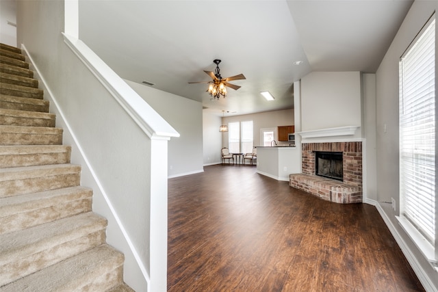 unfurnished living room featuring vaulted ceiling, a brick fireplace, hardwood / wood-style floors, and ceiling fan