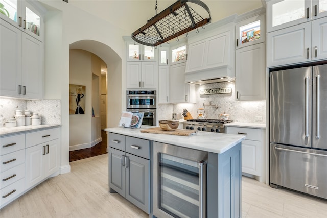 kitchen featuring appliances with stainless steel finishes, beverage cooler, white cabinets, and backsplash