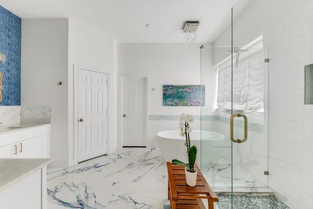 bathroom featuring marble finish floor, vanity, a freestanding bath, and a stall shower