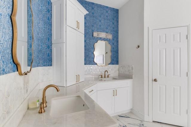 bathroom with marble finish floor, a sink, and backsplash