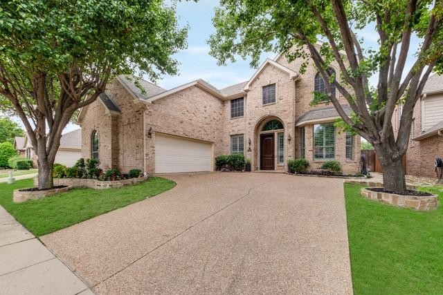 traditional-style house featuring a garage, a front yard, concrete driveway, and brick siding