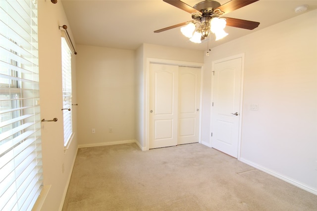 unfurnished bedroom featuring light colored carpet, ceiling fan, and a closet