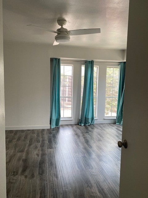 empty room featuring dark hardwood / wood-style flooring, ceiling fan, and plenty of natural light