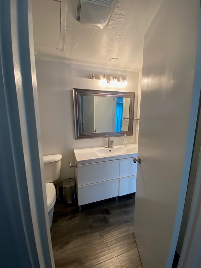 bathroom featuring vanity with extensive cabinet space, hardwood / wood-style floors, and toilet