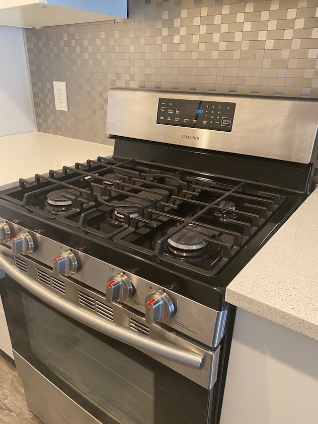 interior details with light stone counters, tasteful backsplash, and stainless steel gas stove