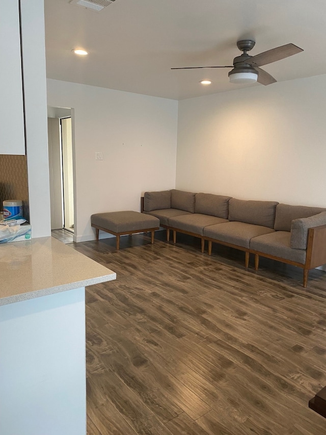 living room with dark wood-type flooring and ceiling fan