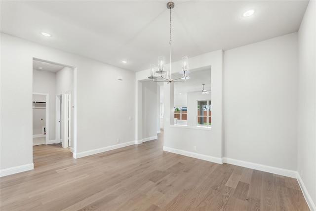 unfurnished dining area featuring ceiling fan with notable chandelier and light hardwood / wood-style floors