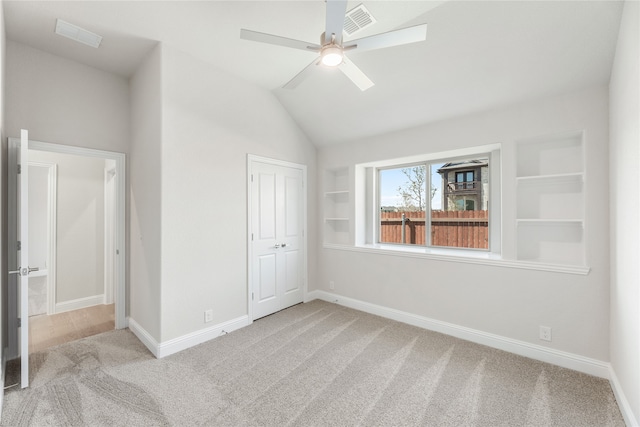 unfurnished bedroom featuring lofted ceiling, light colored carpet, and ceiling fan