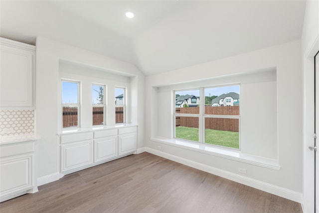 unfurnished room featuring vaulted ceiling, light hardwood / wood-style flooring, and plenty of natural light