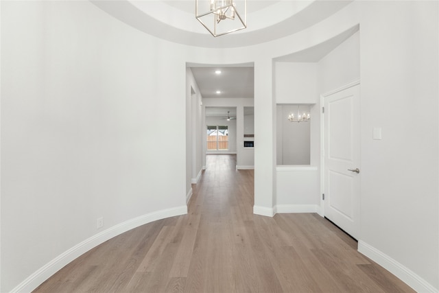 corridor with a notable chandelier and light wood-type flooring