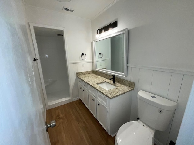 bathroom featuring a shower, crown molding, toilet, vanity, and hardwood / wood-style flooring