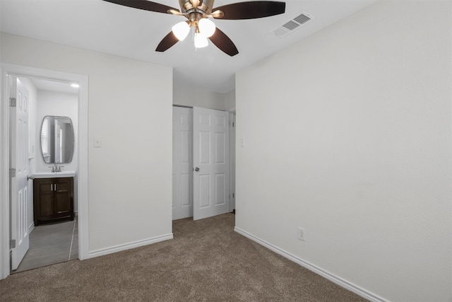 unfurnished bedroom with carpet flooring, ensuite bath, ceiling fan, and sink