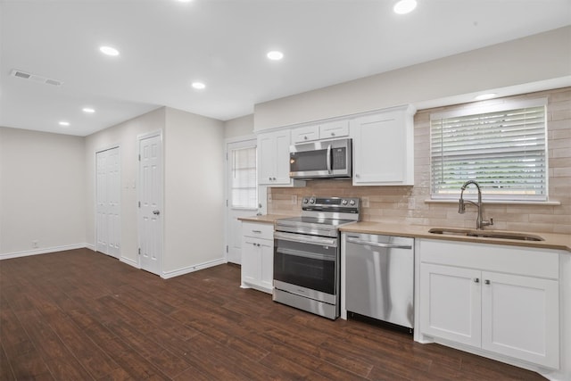 kitchen featuring appliances with stainless steel finishes, backsplash, white cabinets, sink, and dark hardwood / wood-style flooring