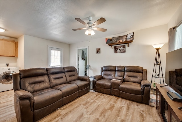 living room with light hardwood / wood-style flooring, ceiling fan, and washer / dryer