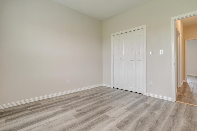 unfurnished bedroom with a closet and light wood-type flooring