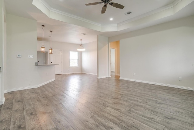 unfurnished living room with crown molding, wood-type flooring, ceiling fan, and a tray ceiling