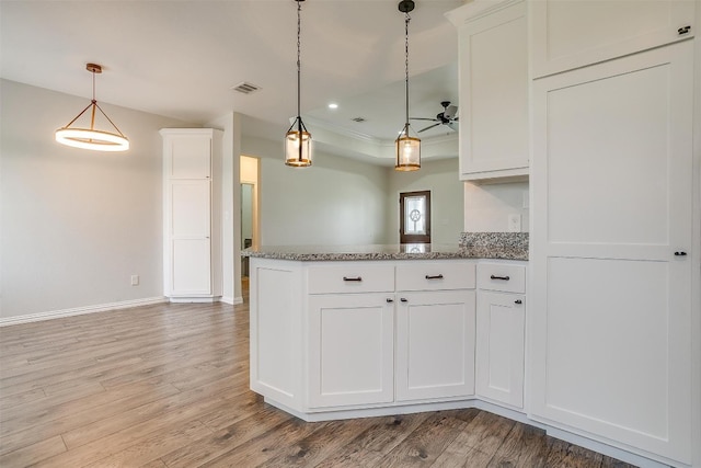 kitchen with pendant lighting, dark stone countertops, white cabinetry, and hardwood / wood-style floors