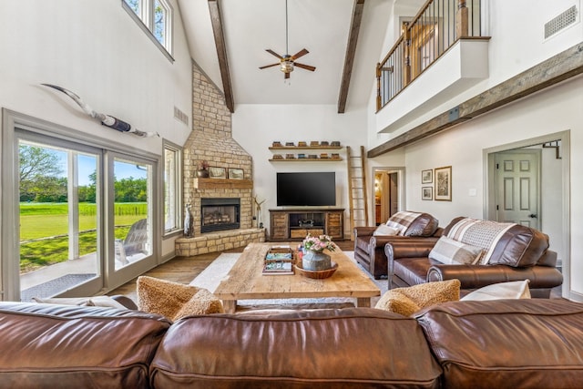 living room with high vaulted ceiling, beamed ceiling, a brick fireplace, brick wall, and ceiling fan