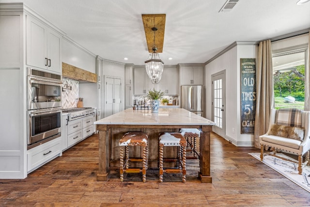 kitchen featuring appliances with stainless steel finishes, a center island, hanging light fixtures, dark hardwood / wood-style floors, and light stone countertops