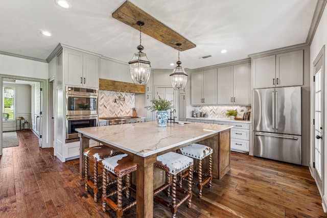 kitchen featuring appliances with stainless steel finishes, tasteful backsplash, dark hardwood / wood-style flooring, and an island with sink