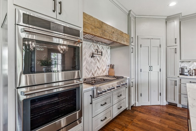 kitchen featuring light stone countertops, dark hardwood / wood-style floors, appliances with stainless steel finishes, custom range hood, and tasteful backsplash