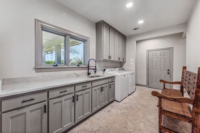 kitchen with light stone countertops, light tile flooring, washer and clothes dryer, gray cabinets, and sink