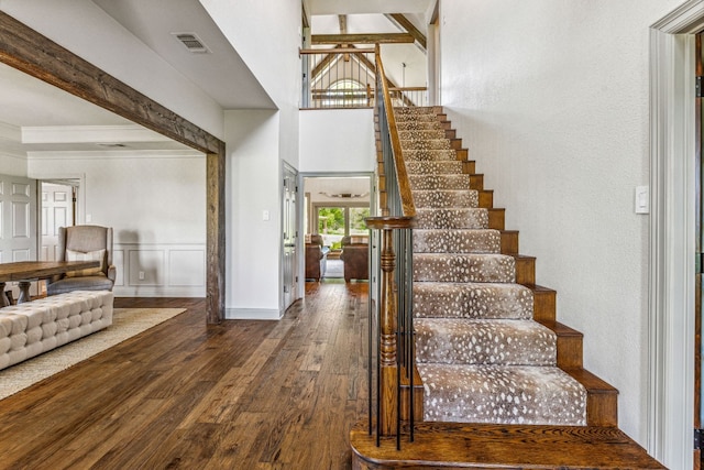 stairs with wood-type flooring and beam ceiling